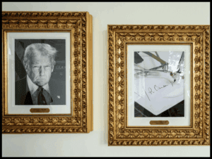 A black and white portrait of former U.S. President Donald Trump hung in an ornate gold frame.