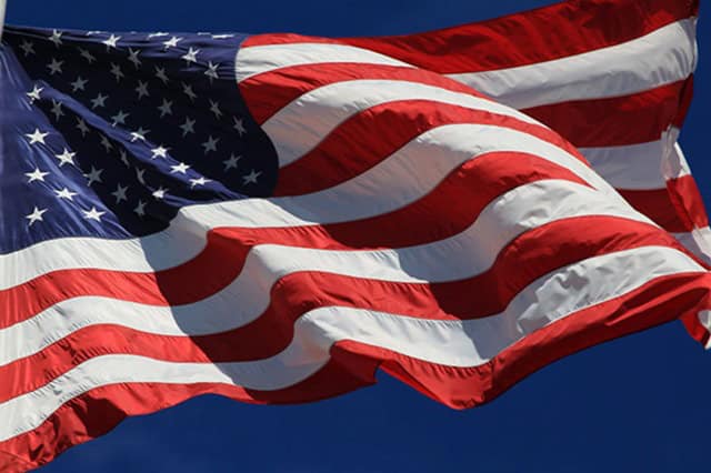 U.S. flag waving against a clear blue sky, symbolizing American patriotism and freedom. Perfect for topics related to U.S. politics, patriotic activism, and civic engagement on One Citizen Speaking.