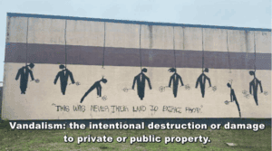 Graffiti mural depicting fallen figures representing land destruction, with the phrase "This was never their land to extract from," highlighting themes of land rights and environmental activism.