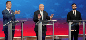 Debate stages featuring three male politicians at podiums during a political event with a blue and red background.